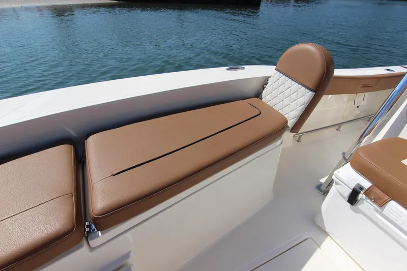 Slide: The Image of 2022 Pioneer 220 Bay Sport boat interior with brown cushioned seating by the water. - 10