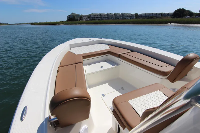 Slide: The Image of 2022 Pioneer 220 Bay Sport boat with brown seating, on calm water near shoreline. - 11
