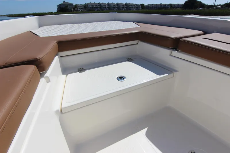 Slide: The Image of 2022 Pioneer 220 Bay Sport boat interior with brown seating and storage compartment. - 12