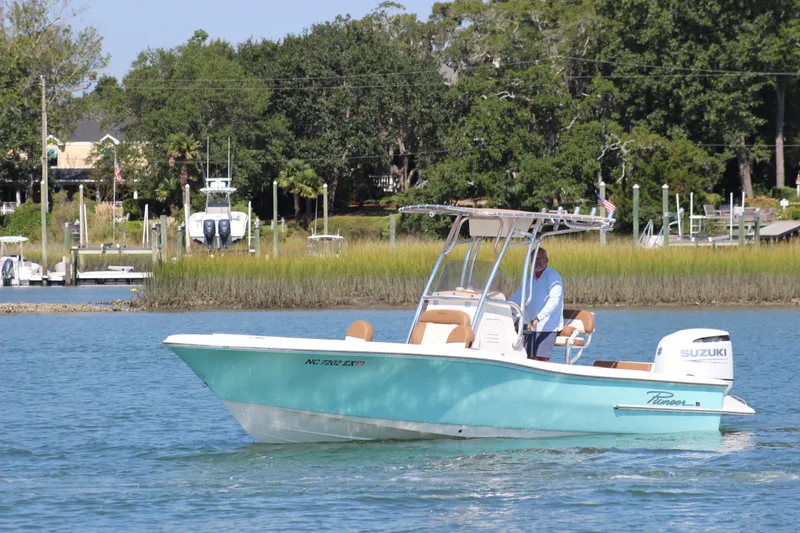 Slide: The Image of 2022 Pioneer 220 Bay Sport boat cruising on a calm river with lush greenery. - 2