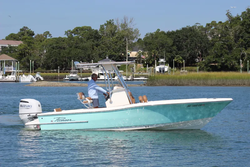 Slide: The Image of 2022 Pioneer 220 Bay Sport boat cruising on a calm waterway with lush greenery. - 7