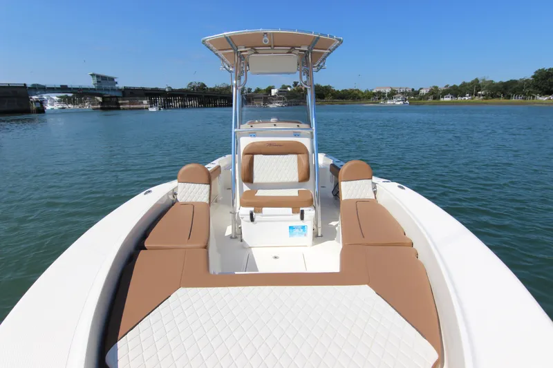 Slide: The Image of 2022 Pioneer 220 Bay Sport boat on calm water, featuring tan seating and T-top. - 9