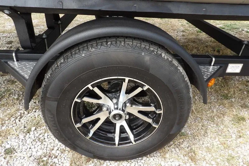 Slide: The Image of 2023 Bennington 20 SVF trailer wheel with black and silver alloy rim on gravel. - 47