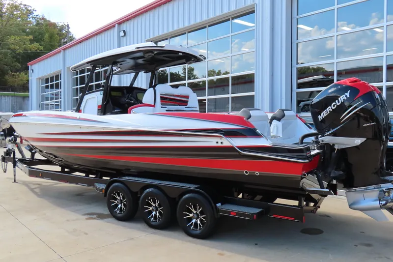 Slide: The Image of 2022 Sunsation 32CCX boat with Mercury engine on a trailer, parked outside a garage. - 2