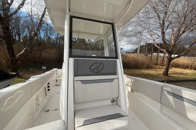 Slide: The Image of 2026 Sailfish 252 CC boat interior with seating and console, surrounded by trees. - 19