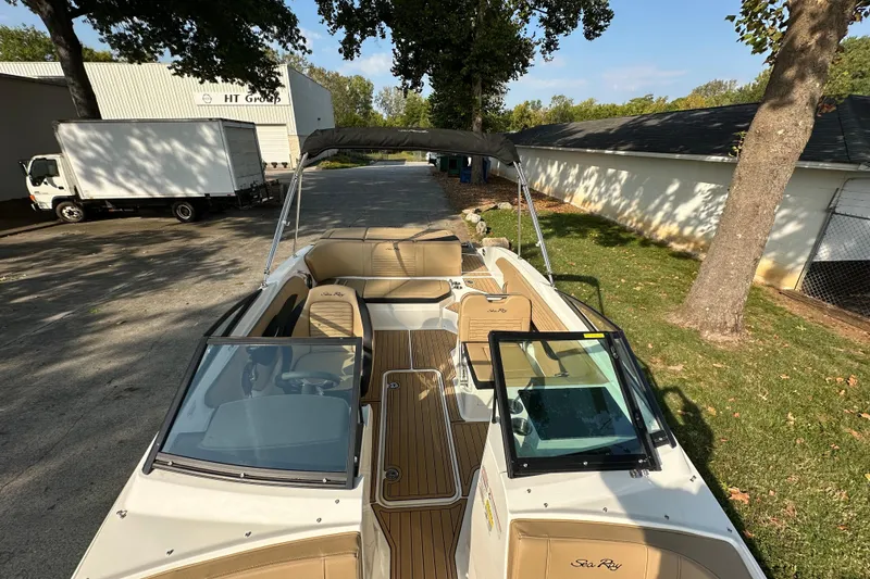 Slide: The Image of 2024 Sea Ray SPX 210 boat with tan interior, parked outdoors near trees and buildings. - 15
