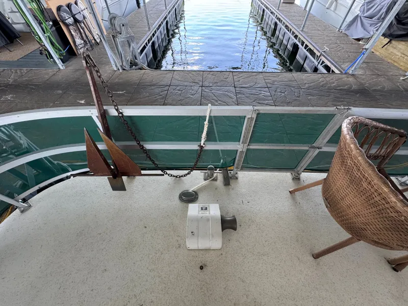 Slide: The Image of Houseboat deck with wicker chair, anchor, and dock view. Gibson 44, 1994 model. - 40