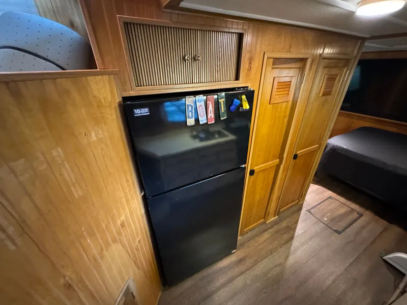 Slide: The Image of Wood-paneled interior with black fridge in a 1994 Gibson 44 boat. - 48