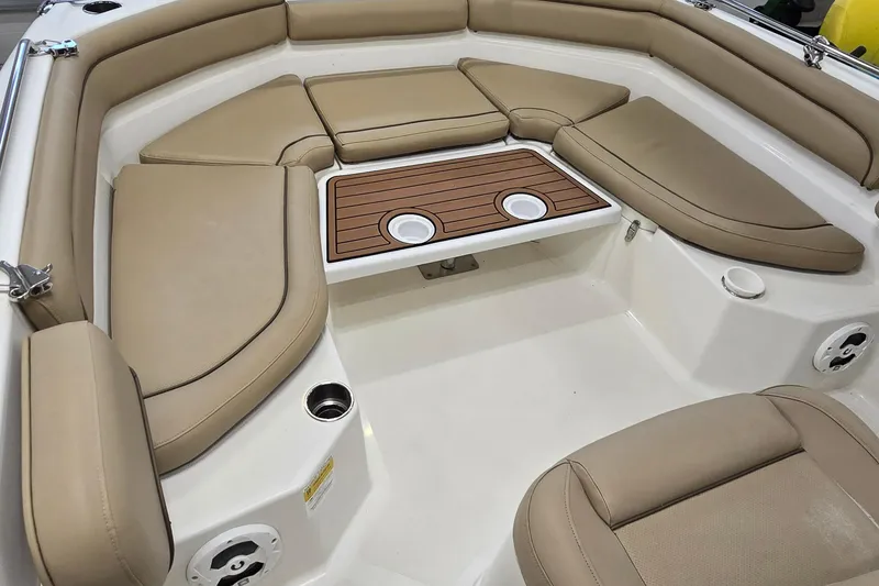 Slide: The Image of 2019 NauticStar 231 Hybrid boat interior with tan cushioned seating and wooden table. - 26
