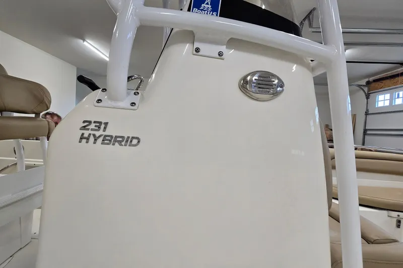 Slide: The Image of 2019 NauticStar 231 Hybrid boat interior with beige seating in a garage. - 28