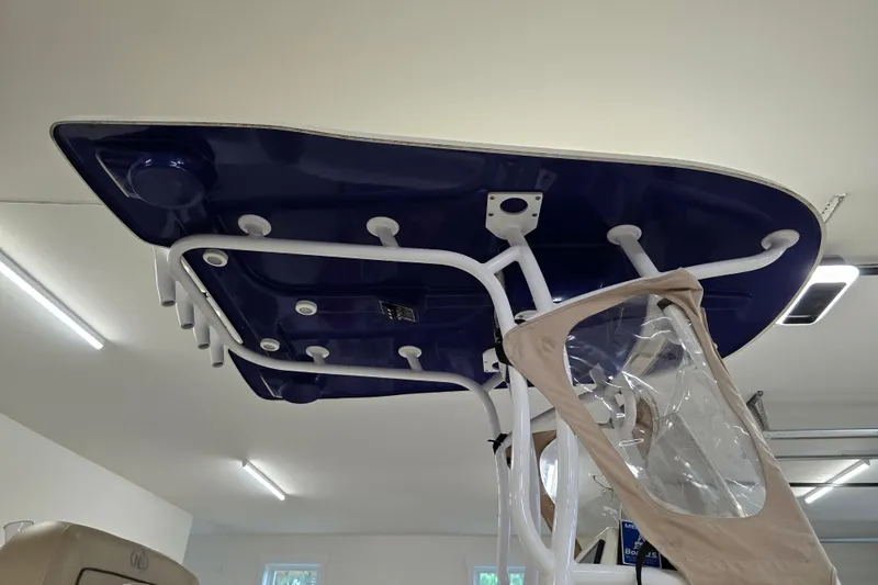 Slide: The Image of 2019 NauticStar 231 Hybrid boat T-top with rod holders and canvas enclosure in a garage. - 39