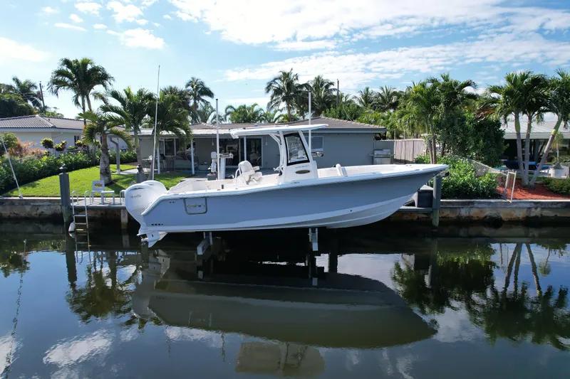 The Image of 2024 Sea Hunt Ultra 275 SE boat docked by waterfront home with palm trees. - 0