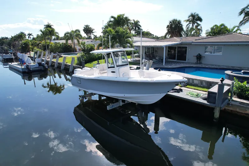 Slide: The Image of 2024 Sea Hunt Ultra 275 SE boat docked by a waterfront home. - 1