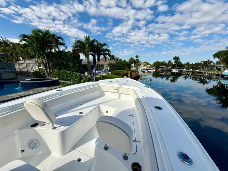 Slide: The Image of 2024 Sea Hunt Ultra 275 SE boat on a calm waterway with palm trees. - 16
