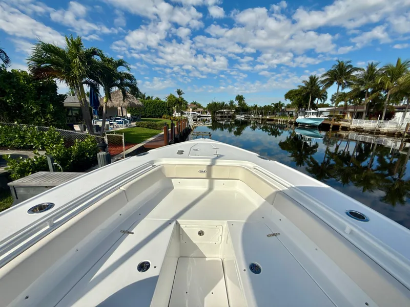Slide: The Image of 2024 Sea Hunt Ultra 275 SE boat docked in a scenic, tropical canal setting. - 17