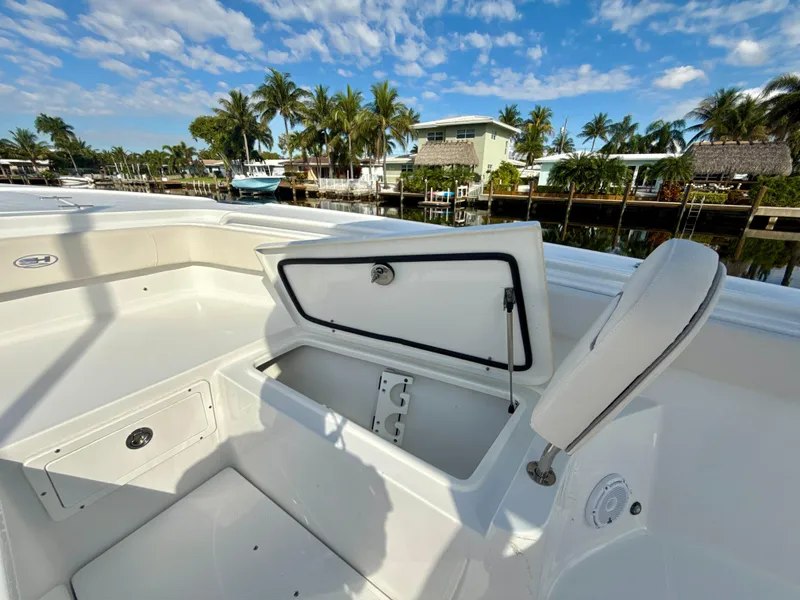 Slide: The Image of 2024 Sea Hunt Ultra 275 SE boat with open storage compartment, docked near palm trees. - 19