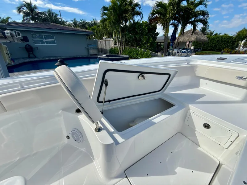 Slide: The Image of 2024 Sea Hunt Ultra 275 SE boat with open storage compartment, poolside setting. - 20