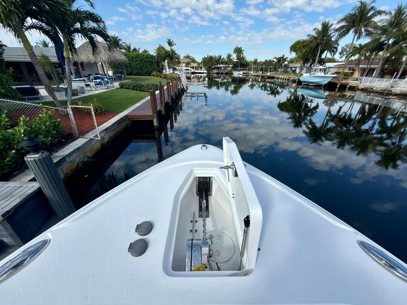 Slide: The Image of 2024 Sea Hunt Ultra 275 SE boat on a calm canal with palm trees. - 21