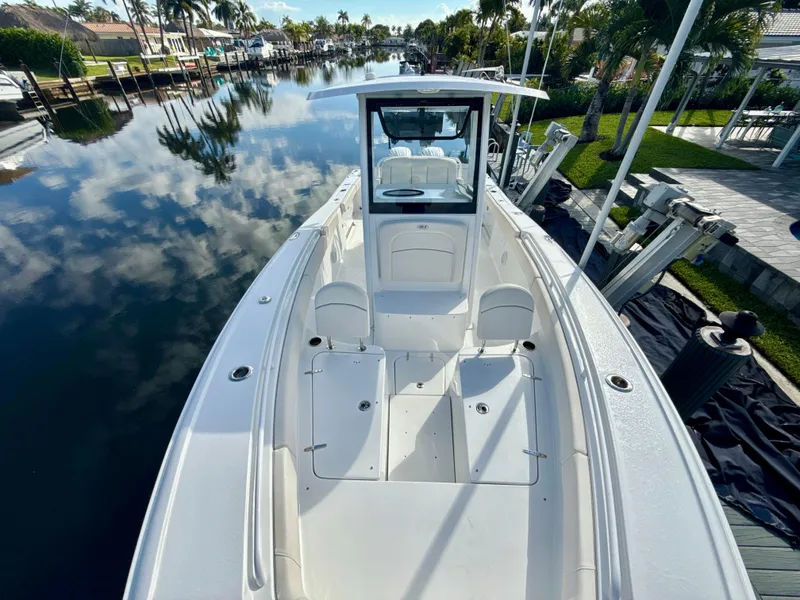 Slide: The Image of 2024 Sea Hunt Ultra 275 SE boat docked on a calm, reflective waterway. - 22