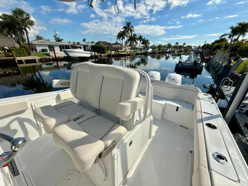 Slide: The Image of 2024 Sea Hunt Ultra 275 SE boat with luxurious seating, docked in a scenic canal. - 23
