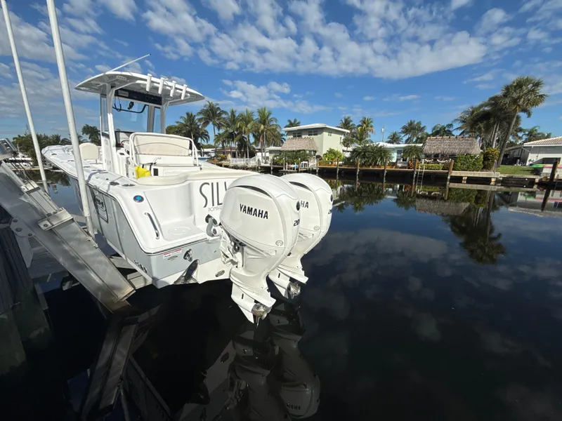 Slide: The Image of 2024 Sea Hunt Ultra 275 SE boat docked by a calm waterfront. - 28