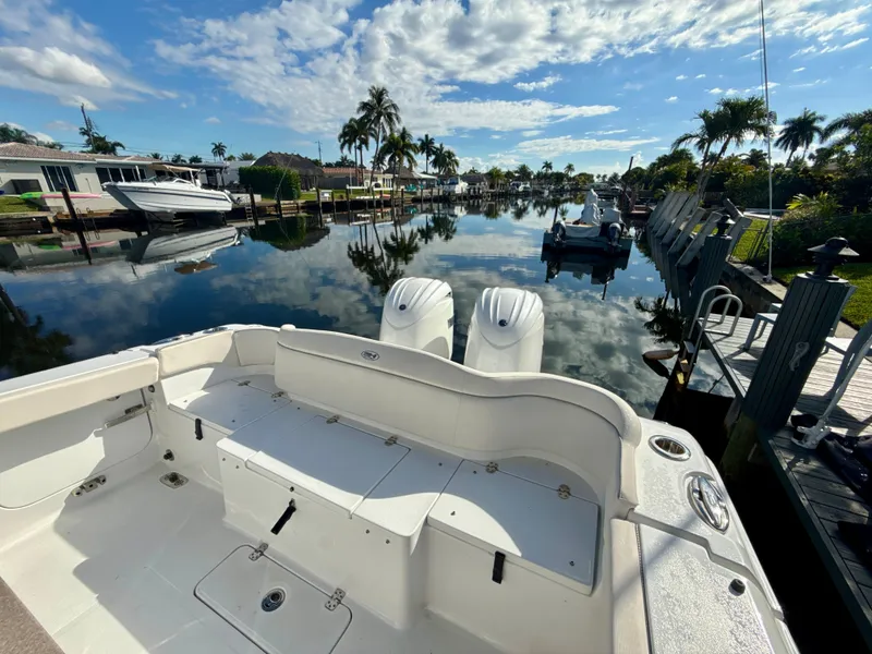 Slide: The Image of 2024 Sea Hunt Ultra 275 SE boat docked by a serene waterfront with palm trees. - 5