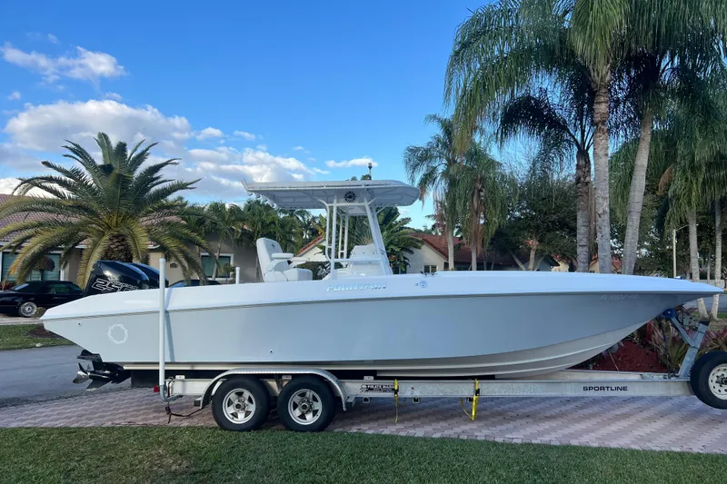 The Image of 2002 Fountain 29 Center Console boat on trailer, surrounded by palm trees and clear sky. - 0