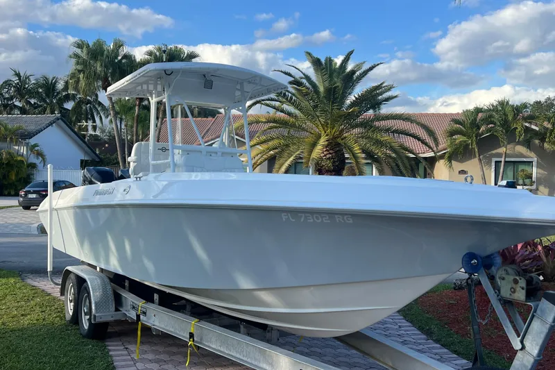 Slide: The Image of 2002 Fountain 29 Center Console boat on trailer, parked in a tropical residential area. - 1