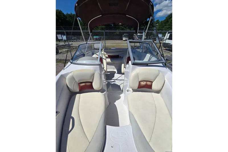 Slide: The Image of 2011 Tahoe Q5i boat interior with white and tan seating, under a sunny sky. - 11