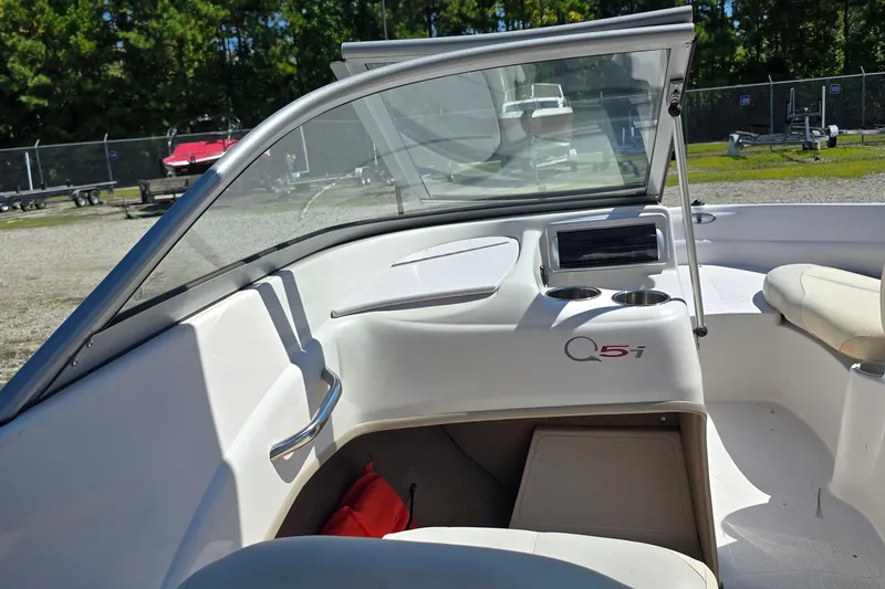 Slide: The Image of 2011 Tahoe Q5i boat interior with windshield, cup holders, and seating in a sunny outdoor setting. - 24