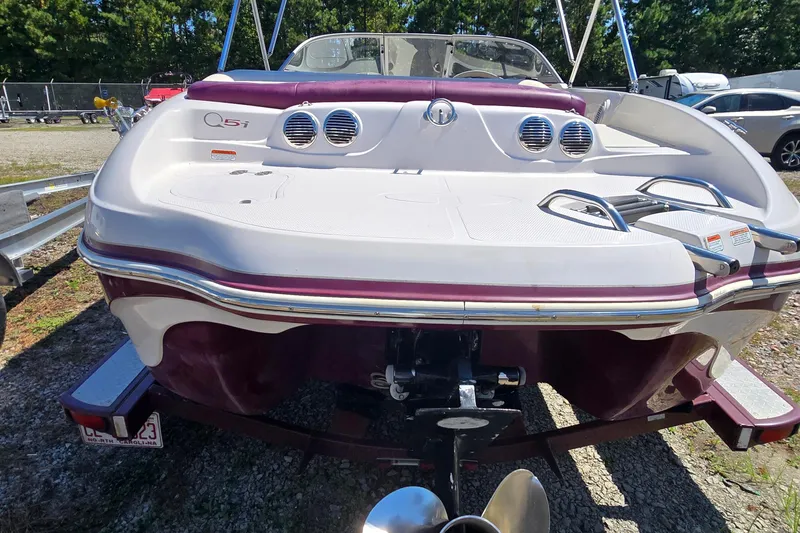 Slide: The Image of 2011 Tahoe Q5i boat rear view with maroon and white design, parked outdoors. - 4