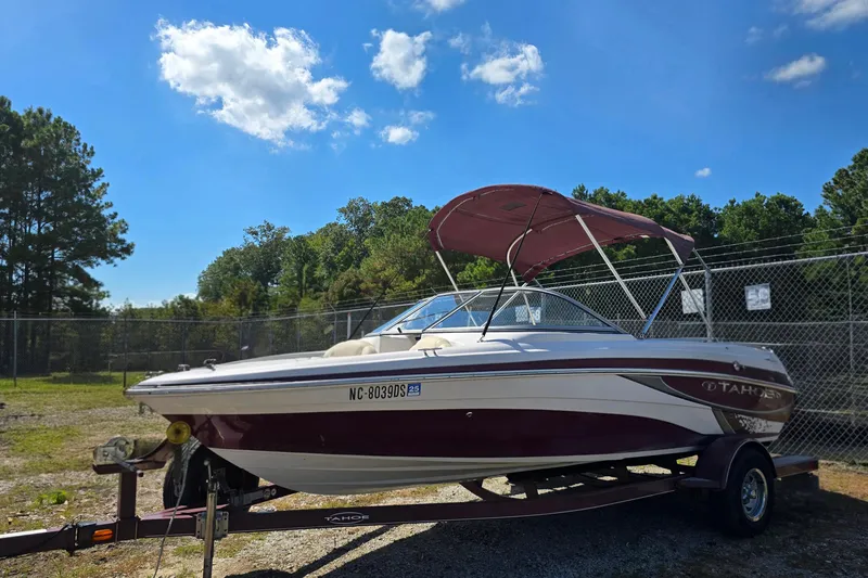 Slide: The Image of 2011 Tahoe Q5i boat with canopy on trailer, parked outdoors under blue sky. - 6