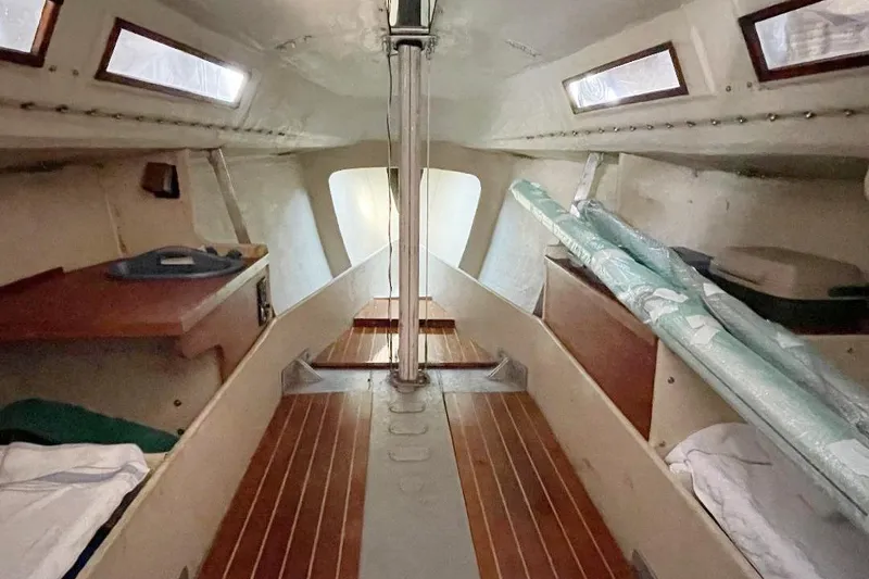 Slide: The Image of 1985 S2 K sailboat interior with wooden flooring and compact cabin layout. - 9