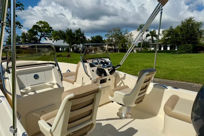 Slide: The Image of 2026 Scout 175 Sport Dorado boat interior with steering wheel and seating, under a cloudy sky. - 10