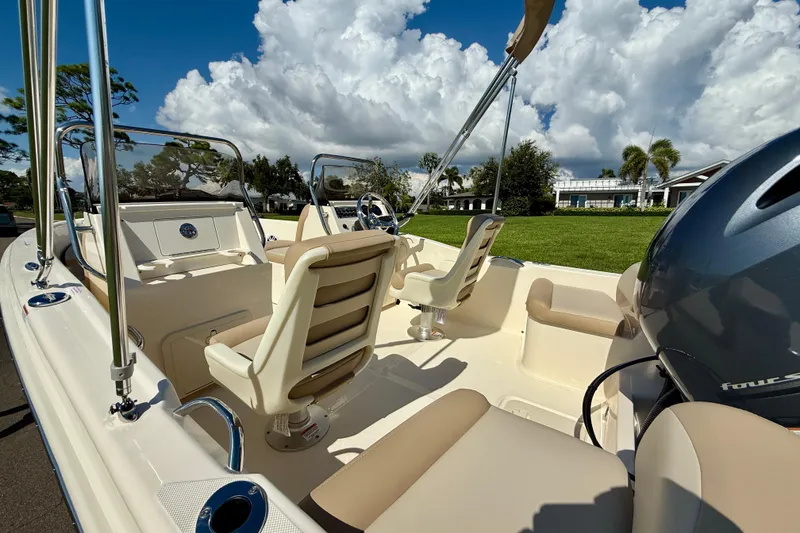 Slide: The Image of 2026 Scout 175 Sport Dorado boat interior with seating and steering wheel, under a cloudy sky. - 13