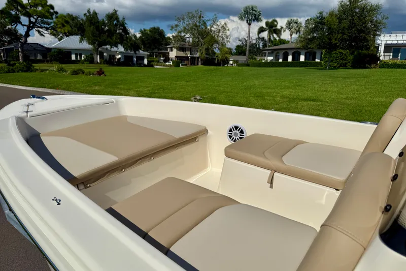 Slide: The Image of 2026 Scout 175 Sport Dorado boat interior with beige seating, set against a lush green landscape. - 20