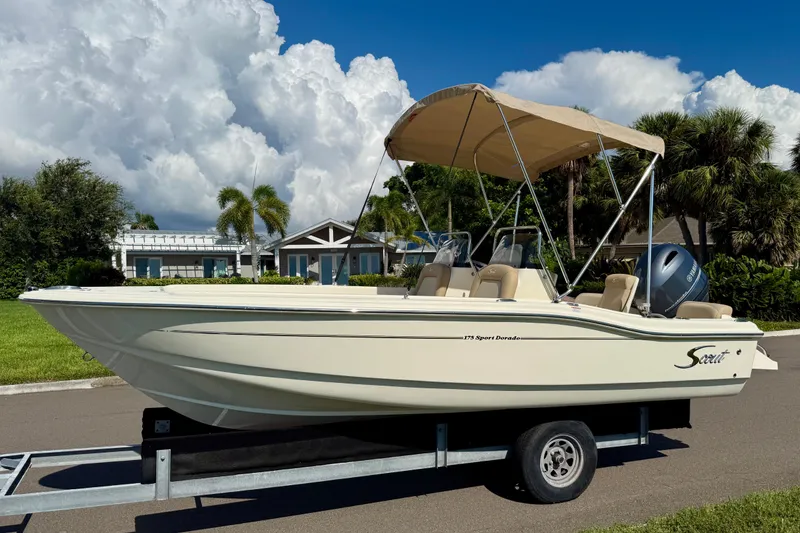 Slide: The Image of 2026 Scout 175 Sport Dorado boat on trailer, parked outdoors under a clear sky. - 5