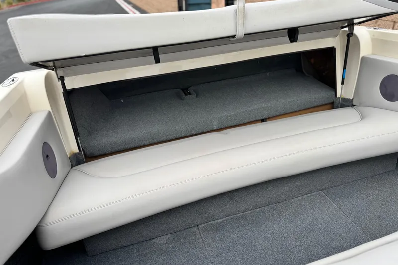 Slide: The Image of 1999 Malibu Sunsetter LX boat interior with open storage compartment and cushioned seating. - 16