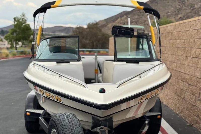 Slide: The Image of 1999 Malibu Sunsetter LX boat on trailer, parked near a stone wall. - 2