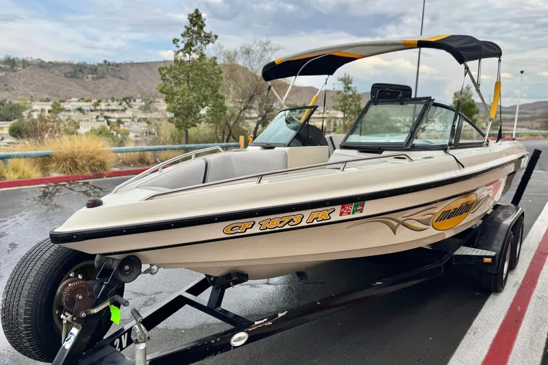 Slide: The Image of 1999 Malibu Sunsetter LX boat on trailer, parked outdoors with scenic background. - 3
