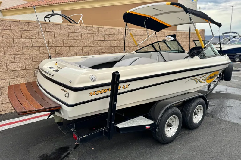 Slide: The Image of 1999 Malibu Sunsetter LX boat on trailer, featuring a sleek design and wooden swim platform. - 5