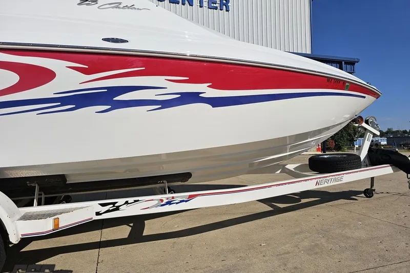 Slide: The Image of 2005 Baja 23 Outlaw boat with red and blue graphics on a trailer. - 10