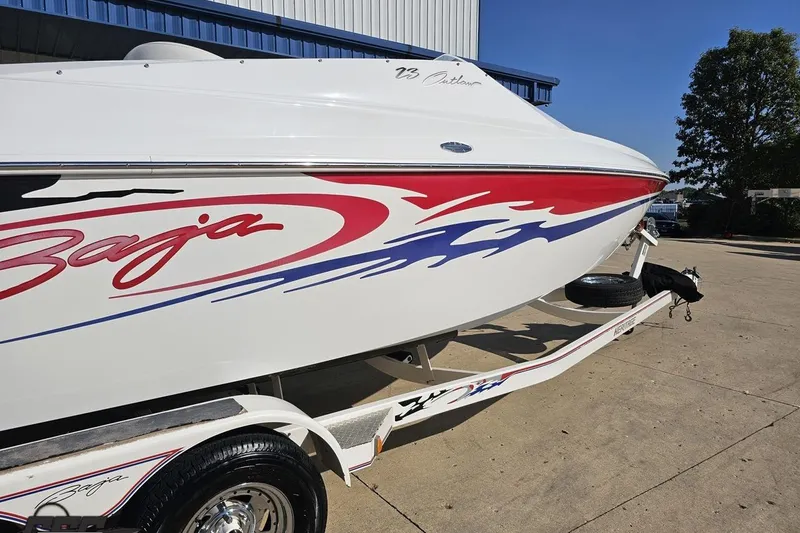 Slide: The Image of 2005 Baja 23 Outlaw boat with vibrant red and blue graphics on a trailer. - 12