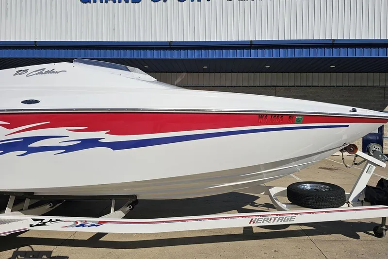 Slide: The Image of 2005 Baja 23 Outlaw speedboat with red and blue graphics on a trailer. - 16