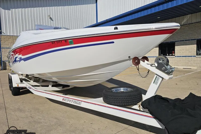 Slide: The Image of 2005 Baja 23 Outlaw boat on trailer, white with red and blue accents, parked outside. - 18