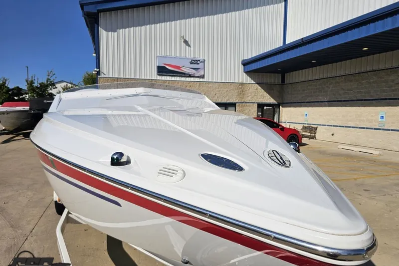 Slide: The Image of 2005 Baja 23 Outlaw boat with sleek white design, parked outside a building. - 19