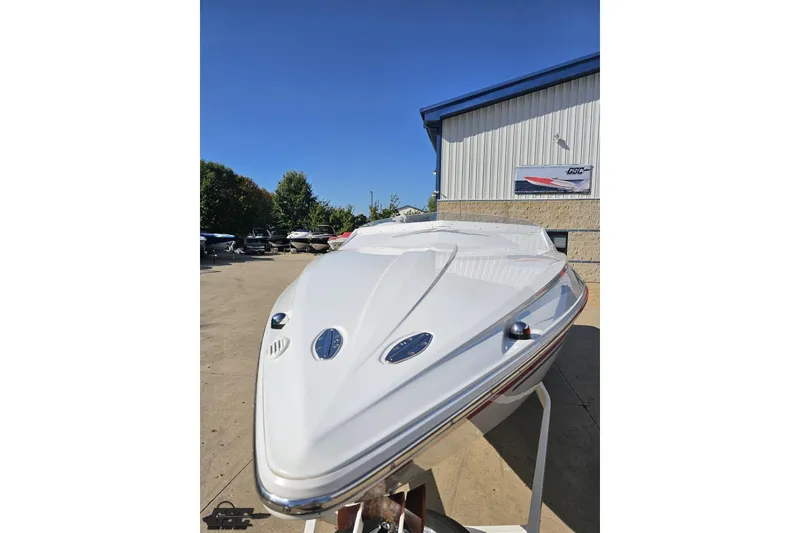 Slide: The Image of 2005 Baja 23 Outlaw boat with sleek white hull, parked outdoors under clear blue sky. - 20