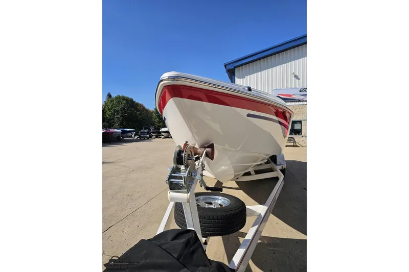 Slide: The Image of 2005 Baja 23 Outlaw boat on trailer, red and white design, parked outdoors. - 21