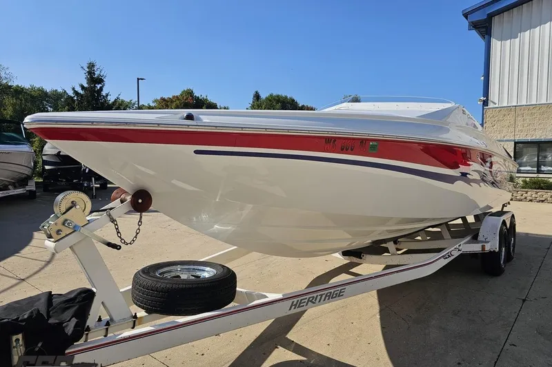 Slide: The Image of 2005 Baja 23 Outlaw boat on trailer, white with red accents, parked outdoors. - 22