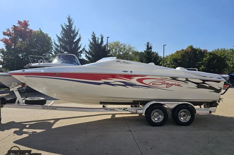 Slide: The Image of 2005 Baja 23 Outlaw speedboat on trailer, vibrant graphics, parked outdoors. - 25